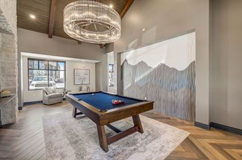 A pool table in a living room with a chandelier